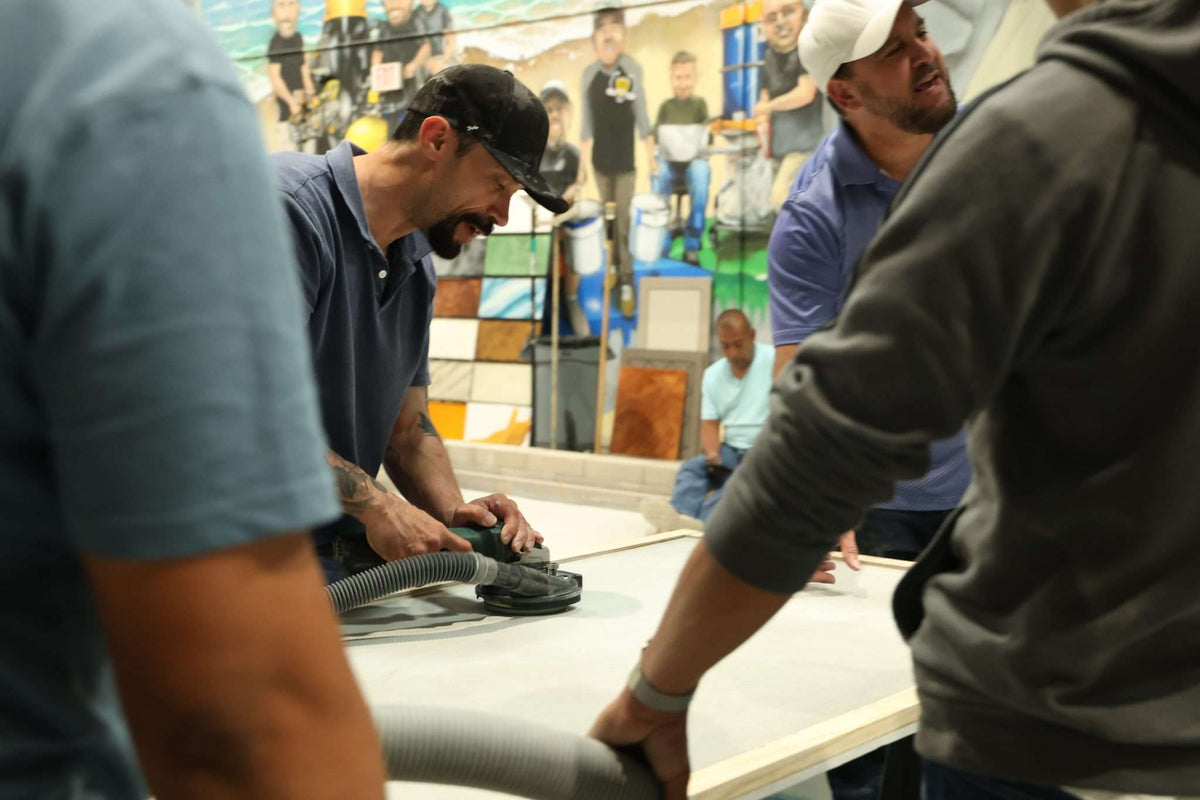 A class of epoxy resin contractors in training at Epoxy Classes working on a sample slab of concrete.