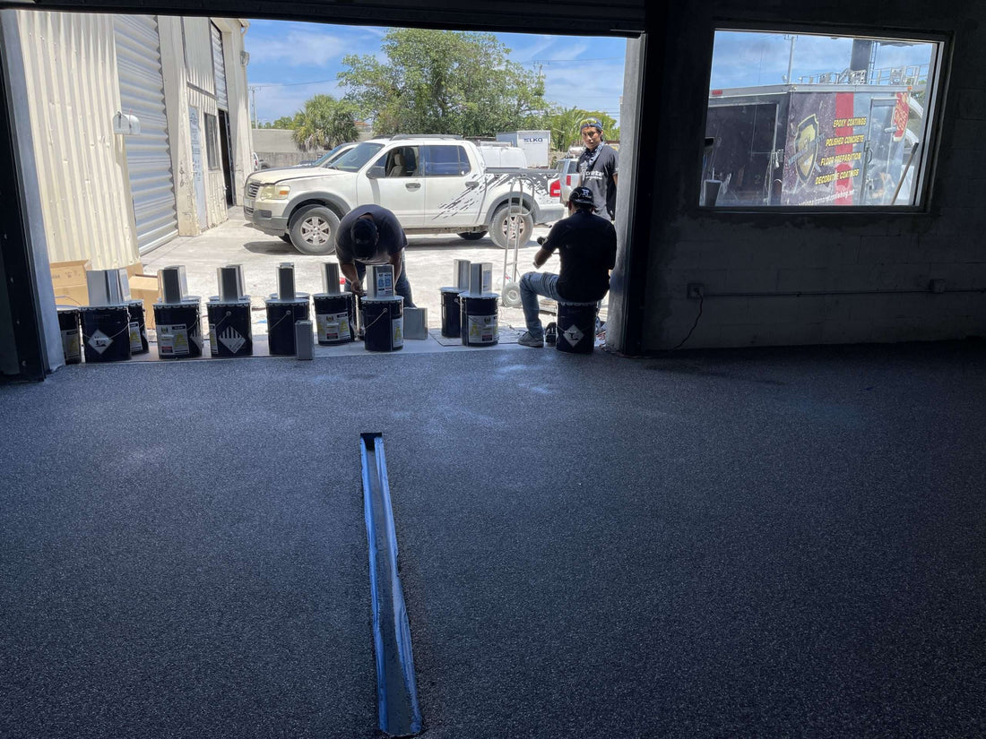 An image showing flooring technicians preparing a large garage for epoxy installation.