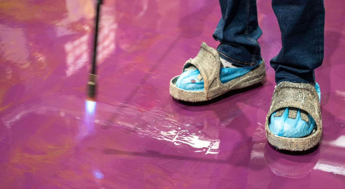 Glossy epoxy resin flooring undergoing treatment for air bubbles.
