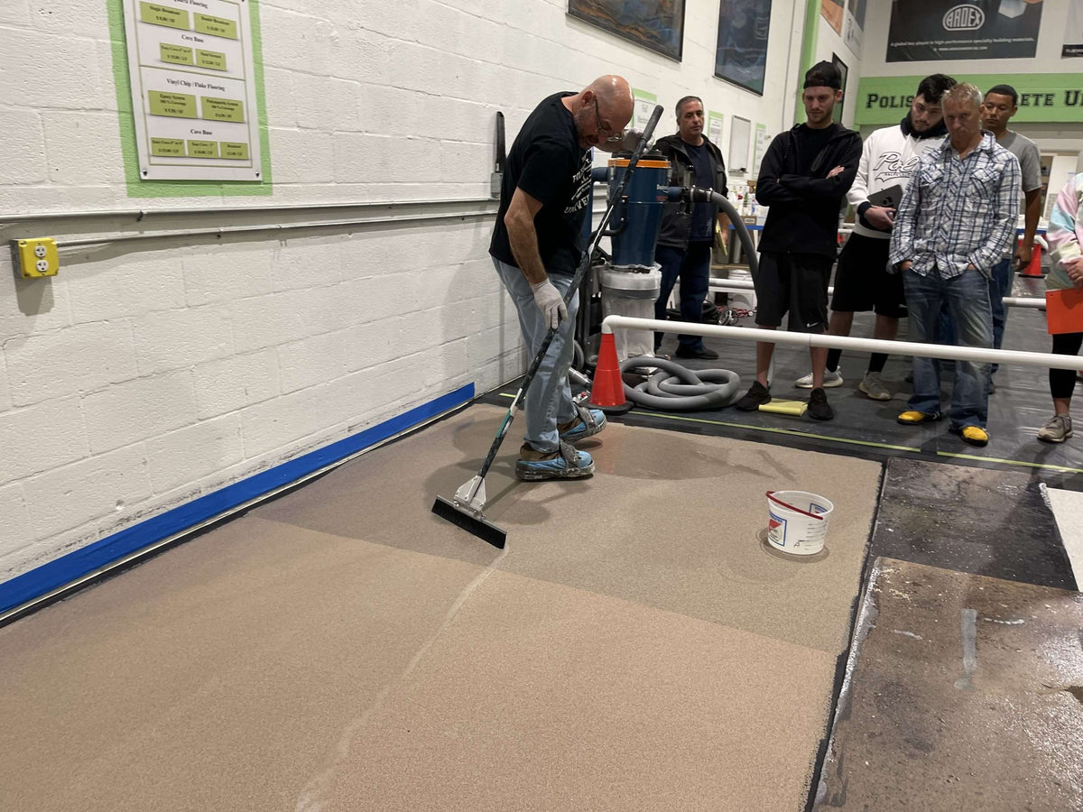 An image showing a professional teaching flooring contractors how to use an epoxy application tool.