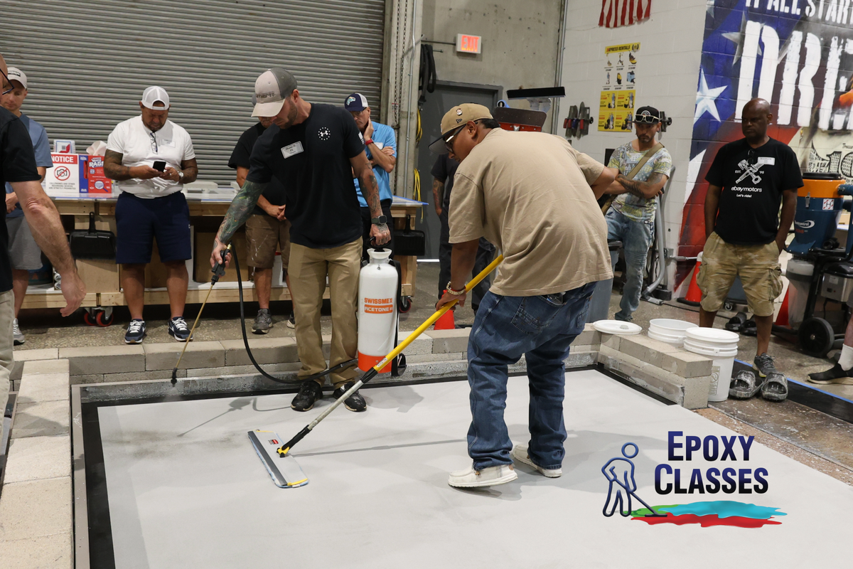 Epoxy flooring training in a warehouse setting with contractors applying resinous coatings.
